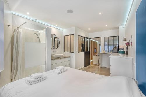 - une chambre blanche avec un grand lit et une salle de bains dans l'établissement LE PHARE - au cœur du quartier des chalets, à Toulouse