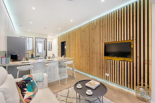 un salon avec un canapé et une télévision sur un mur dans l'établissement LE PHARE - au cœur du quartier des chalets, à Toulouse