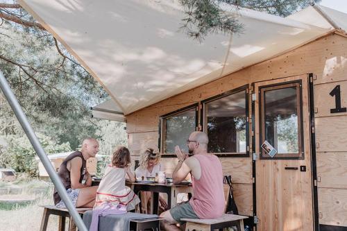 a group of people sitting at a table outside of a caravan at destinature Dorf Hitzacker in Hitzacker