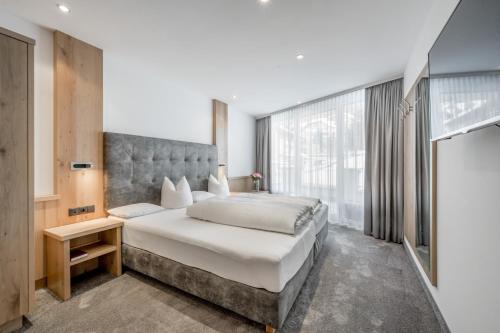 a bedroom with a large bed and a large window at Hotel Garni Christine in Ischgl