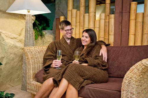 a man and woman sitting on a couch with glasses of wine at TLH Toorak Hotel - TLH Leisure, Entertainment and Spa Resort in Torquay