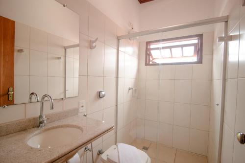 een badkamer met een wastafel, een toilet en een spiegel bij Pouse no Jardim in Pirenópolis