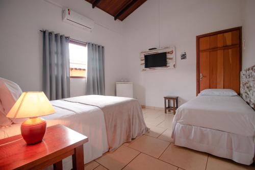 1 dormitorio con 2 camas y mesa con lámpara en Pouse no Jardim, en Pirenópolis