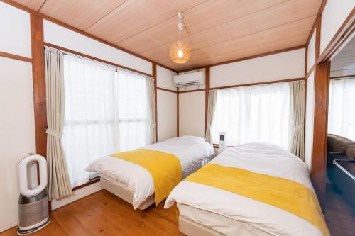 two beds in a room with windows at Pine Tree in Kamakura