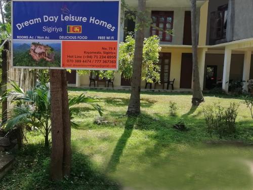 a sign in the grass in front of a building at Dream Day Leisure Homes in Sigiriya
