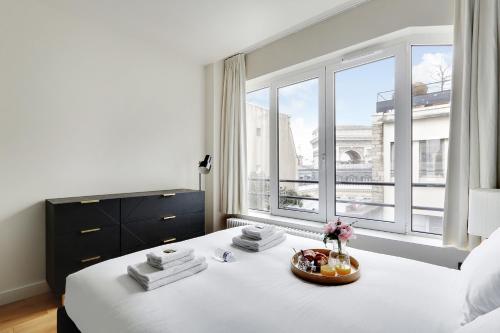 a bedroom with a white bed with a large window at Amazing apartments - Arc de Triomphe-Champs Elysée in Paris