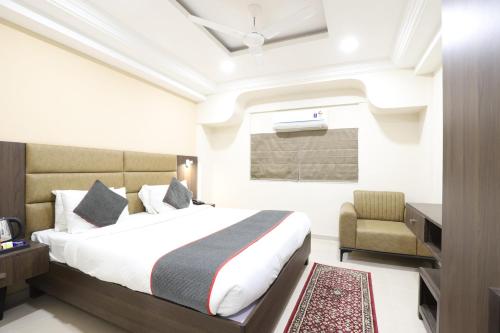 a hotel room with a bed and a chair at Alba Premier, Ahmedabad in Ahmedabad