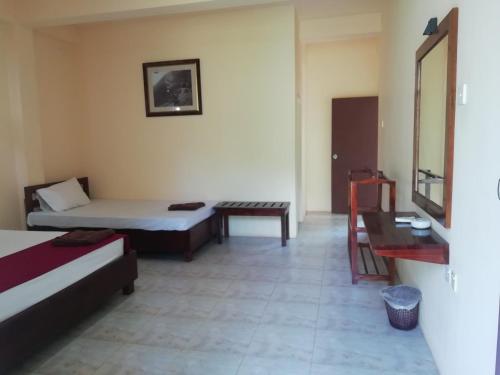 a room with two beds and a bench and a table at Dream Day Leisure Homes in Sigiriya