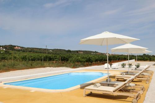 a swimming pool with chairs and umbrellas at Quinta do Barreiro in Borba