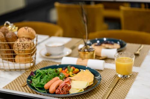 a table with a plate of food and a glass of orange juice at Emerald Hotel by Continental Group in Budapest