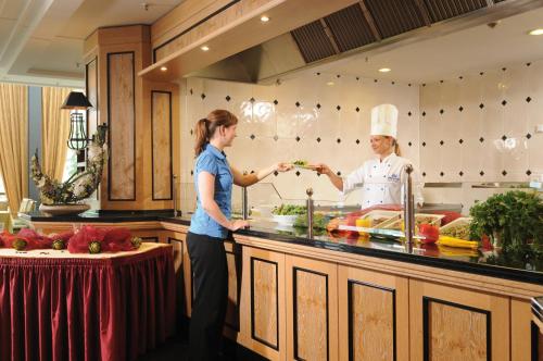 two women are standing in a kitchen preparing food at Maritim Hotel Dresden in Dresden