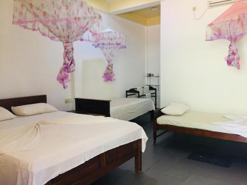 two beds in a room with purple decorations on the wall at Gimansa Rest Sigiriya in Sigiriya