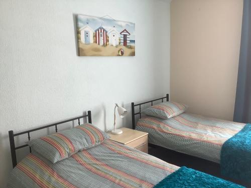 um quarto com duas camas e uma pintura na parede em Whitegate 1st floor Apartment em Llandudno