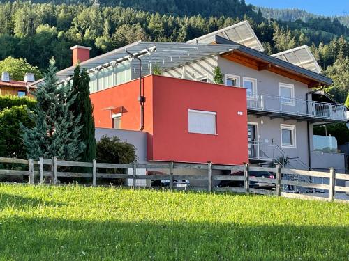uma casa vermelha com uma cerca num campo em Apartments Evandi - Ferienwohnungen in ruhiger Lage em Schwaz