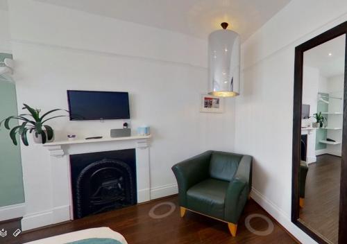 a living room with a green chair and a tv on a fireplace at Hotel Nineteen in Brighton & Hove