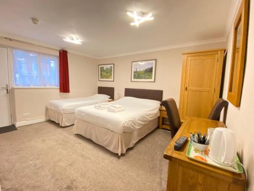a hotel room with two beds and a desk at Fairlawns Guest House in Banbury