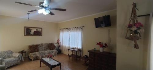 uma sala de estar com um sofá e uma ventoinha de tecto em Casa 200m da praia 3 dorm. p/ 12 pessoas em Peruíbe