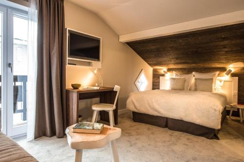 シャモニー・モンブランにあるChalet hôtel le Whymperの大きなベッドとテーブルが備わるホテルルームです。