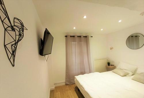 una camera da letto con un letto e una TV a parete di L'auberge aux volets rouges à 4 min du Zoo de Beauval 2-10 pers a Saint-Aignan