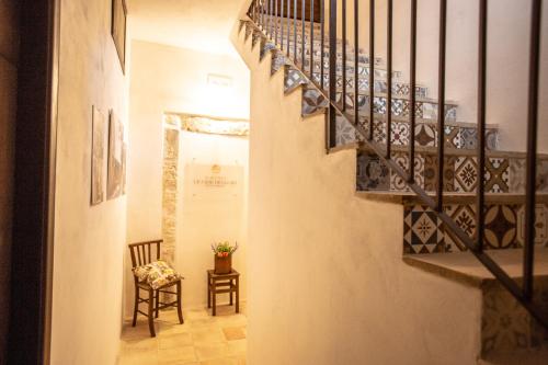 a hallway with a staircase with a chair and a table at SI-Moutique Le Case degli Avi barocche, con terrazza panoramica in Modica