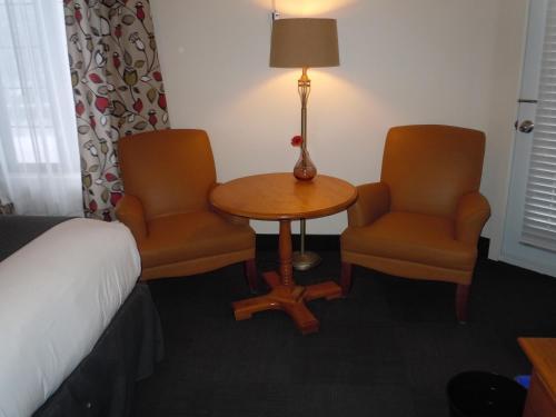 a room with a bed and two chairs and a table and a lamp at L'Auberge Du Lac St-Pierre in Trois-Rivières