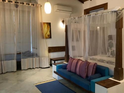 a living room with a blue couch in front of a window at Mind Body and Soul in Dambulla