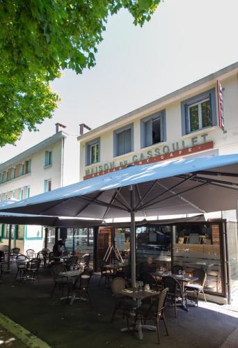 une table avec un parasol devant un bâtiment dans l'établissement Maison du Cassoulet, à Castelnaudary