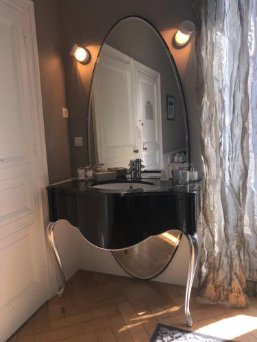 La salle de bains est pourvue d'un lavabo noir et d'un miroir. dans l'établissement La Maison D'Hôtes Nantes Centre, à Nantes