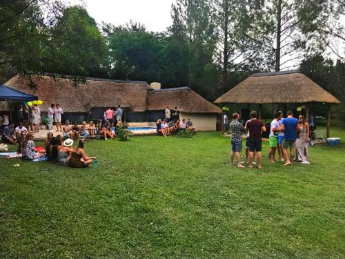 a group of people sitting on the grass in a field at Pine Valley in Lanseria