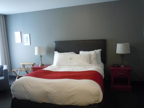 a bedroom with a large bed with red and white sheets at L'Auberge Du Lac St-Pierre in Trois-Rivières