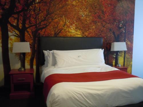 a bedroom with a bed with a painting of trees at L'Auberge Du Lac St-Pierre in Trois-Rivières