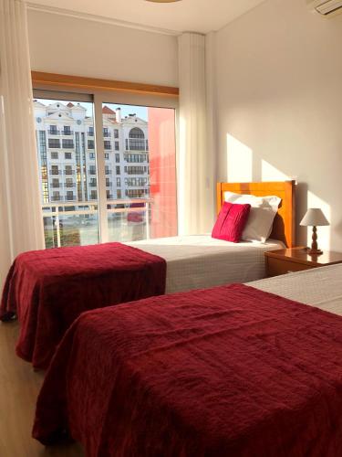 a hotel room with two beds and a window at Alojamentos Campo & Mar - T1 com Piscina in São Martinho do Porto