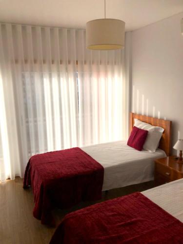 a bedroom with two beds and a large window at Alojamentos Campo & Mar - T1 com Piscina in São Martinho do Porto