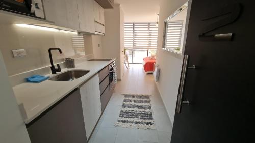 a kitchen with white counters and a sink and a refrigerator at Curitiba VIP Studio 21 in Temuco