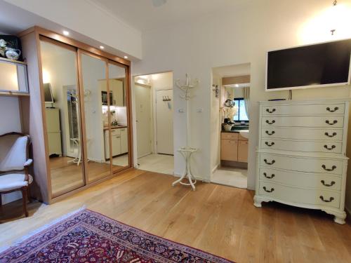 a room with a dresser with a television and a bathroom at Yarden Deluxe Studio Suite in Tel Aviv