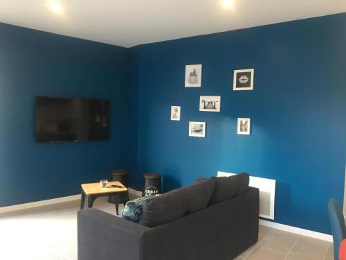 uma sala de estar com um sofá e uma parede azul em Au boitissandeau em Saint-Paul-en-Pareds