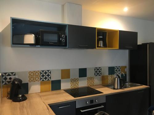 une cuisine avec des placards noirs et un four micro-ondes au-dessus d'un comptoir dans l'établissement Au boitissandeau, à Saint-Paul-en-Pareds