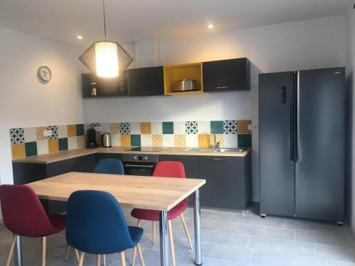 une cuisine avec une table, des chaises et un réfrigérateur dans l'établissement Au boitissandeau, à Saint-Paul-en-Pareds