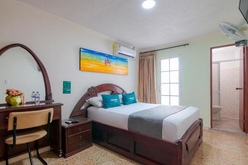 1 dormitorio con cama, escritorio y espejo en Ayenda Jimatta, en Ríohacha