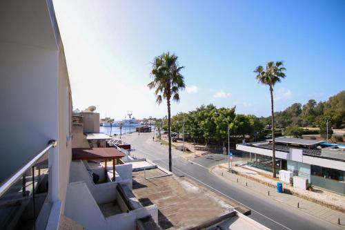 Blick auf eine Straße mit Palmen und ein Gebäude in der Unterkunft Phaedrus Living - Seaside Executive Flat Harbour 205 in Paphos