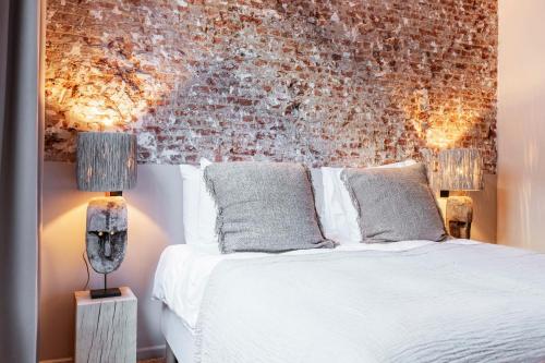 um quarto com uma cama branca e uma parede de tijolos em BTFL Living Antwerp em Antuérpia