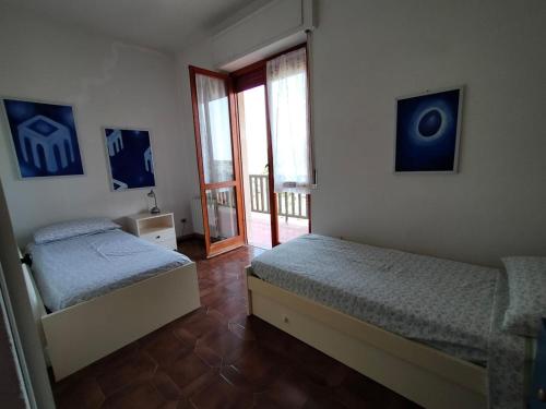 sypialnia z 2 łóżkami i drzwiami na balkon w obiekcie La Casa Bianca - Alghero Calich w mieście Alghero