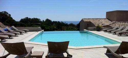une piscine avec des chaises et l'océan en arrière-plan dans l'établissement Résidence A Rundinella, à Porto-Vecchio