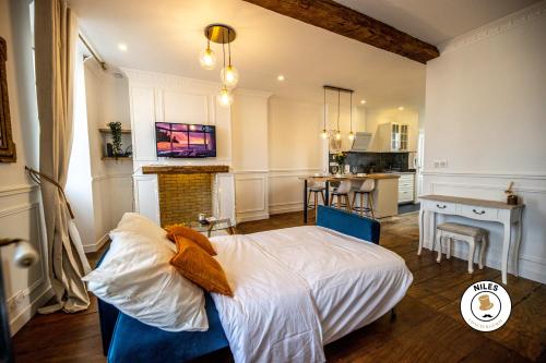 ein Schlafzimmer mit einem Bett und eine Küche mit einem Tisch in der Unterkunft L'Haussmann, Rare, Appartement Vue Château et Palmiers in Pau