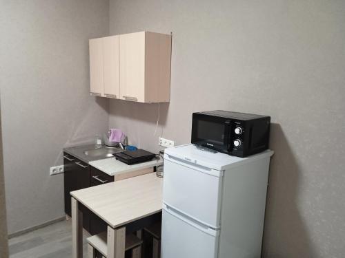 a small kitchen with a microwave on top of a refrigerator at Гостевой дом на Цюрупы 32,Г2 in Sochi
