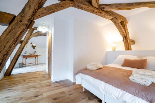 a bedroom with wood floors and a bed in a room with beams at Villa Fémina in Savigny-lès-Beaune