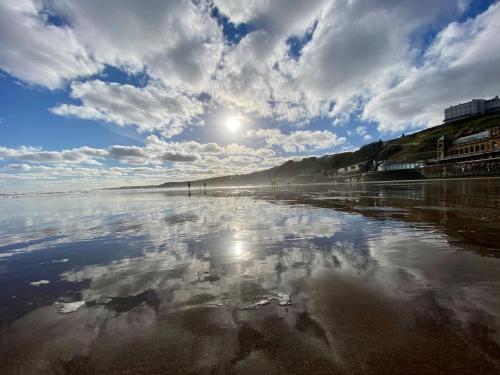 a reflection of the sun in the water on a beach at The Helaina in Scarborough