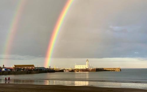 a rainbow over a beach with a pier and the ocean at The Helaina in Scarborough
