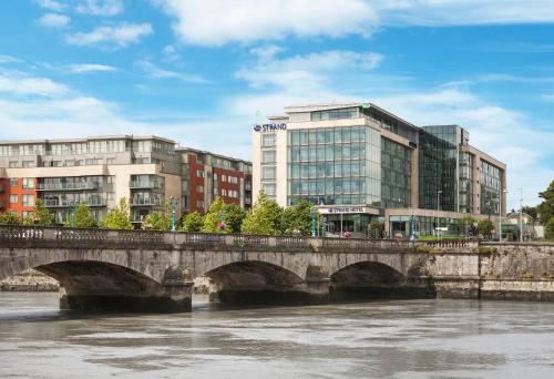 a bridge over a river in front of buildings at Limerick Strand Hotel in Limerick
