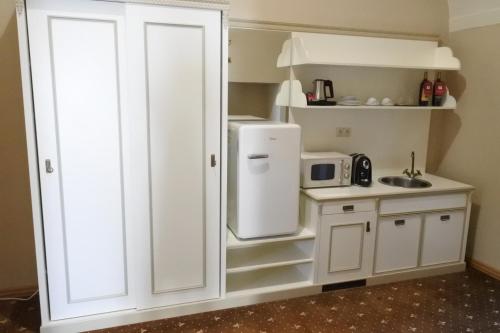 a small kitchen with a white refrigerator and a sink at Hotel Gino Park Palace - Kaštieľ Orlové in Považská Bystrica